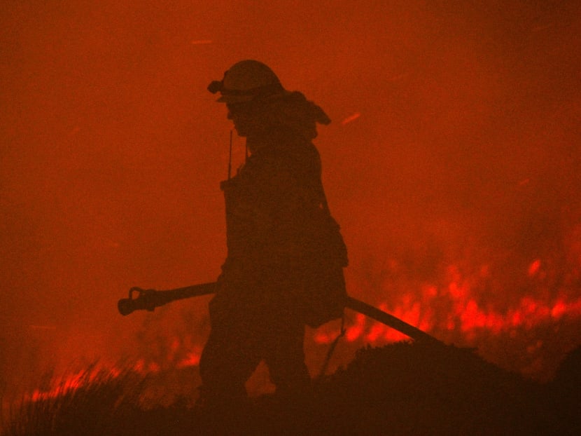 A firefighter holds a hose as the Blue Ridge Fire continues to burn in Yorba Linda, California on Oct 26, 2020.