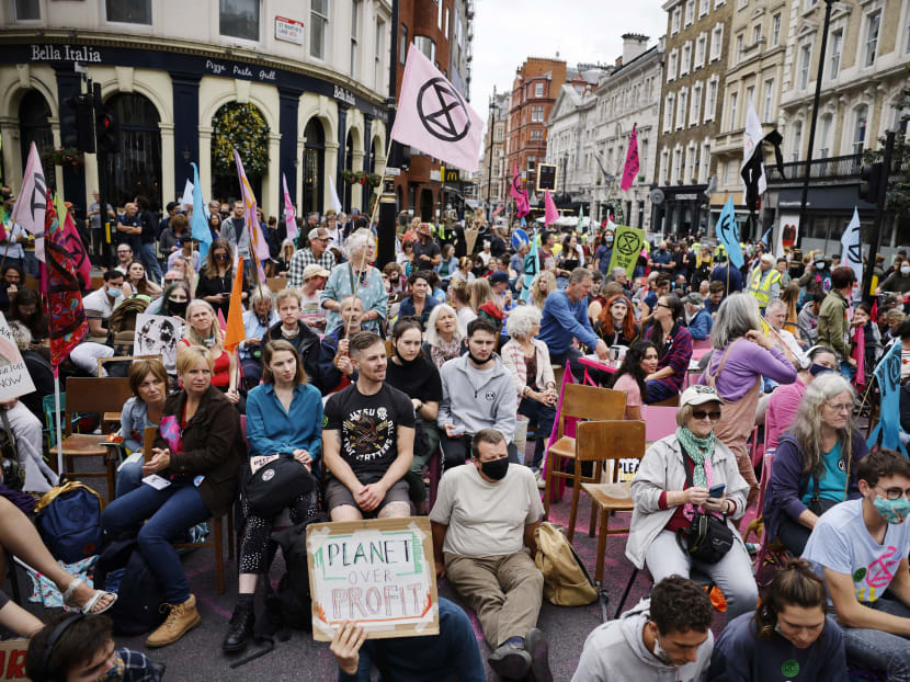 Climate activists from the Extinction Rebellion group sit in the road in central London on  Aug 23, 2021 as the group launched its 'Impossible Rebellion' series of actions to draw attention to the climate crisis and call upon the UK government to take action.