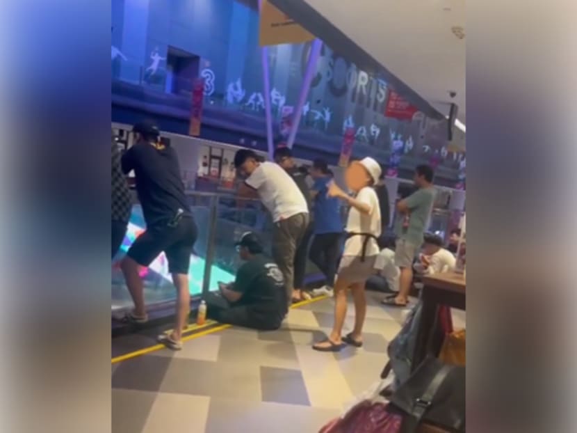 A screengrab of a video clip showing the woman (wearing hat) shouting at two men at Our Tampines Hub. A screengrab of a video clip showing the woman (wearing hat) shouting at two men at Our Tampines Hub.