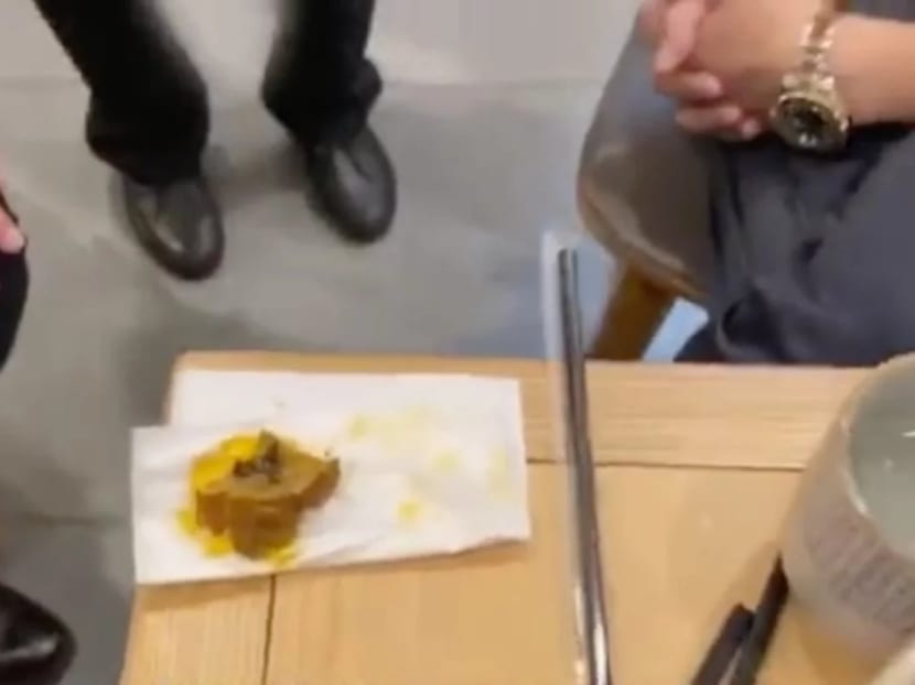 Wang discusses compensation with restaurant staff, who are shown a piece of the pig intestine containing excrement.