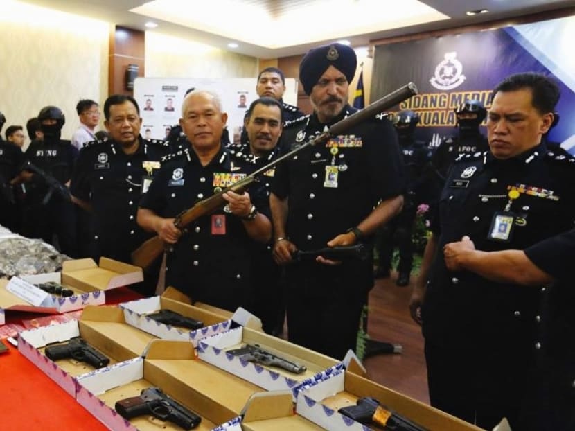 Malaysian police standing around the cache of weapons they seized. Photo: Malay Mail Online