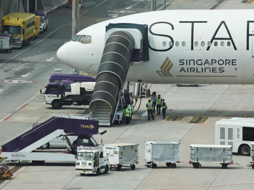 Airport officials standing near the Singapore Airlines aircraft for flight SQ321 parked on the tarmac after an emergency landing at Suvarnabhumi International Airport in Bangkok, Thailand, May 22, 2024.