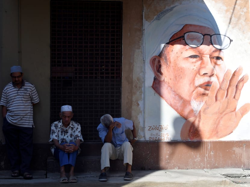 People sit next to a mural of the late former PAS president Nik Abdul Nik Mat at Medan Ilmu in Kota Bharu, Kelantan. The author says that a recent spat between Umno and PAS over the renaming of the Medan Ilmu religious centre to Medan Tok Pa has been cited as an example of it is impossible for the two parties to come together.