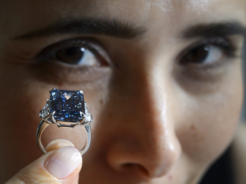 A woman holds up the 'Oppenheimer Blue,' a rare fancy vivid blue diamond weighing 14.62 carat during a press preview by Christies's auction house on May 12, 2016 in Geneva. Photo: AFP