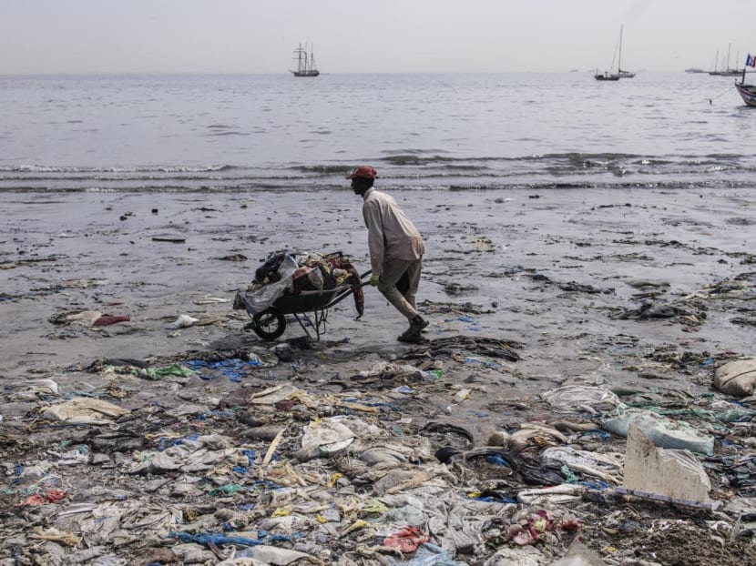 A man pushes a wheelbarrow of waste along Hann Bay in Dakar on Nov 22, 2023. 