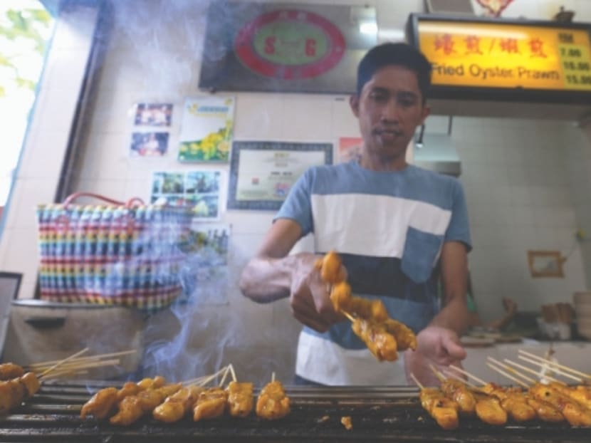 A Myanmar worker is seen grilling satay but the owner claims that he is not actually cooking. Photo: MalayMail