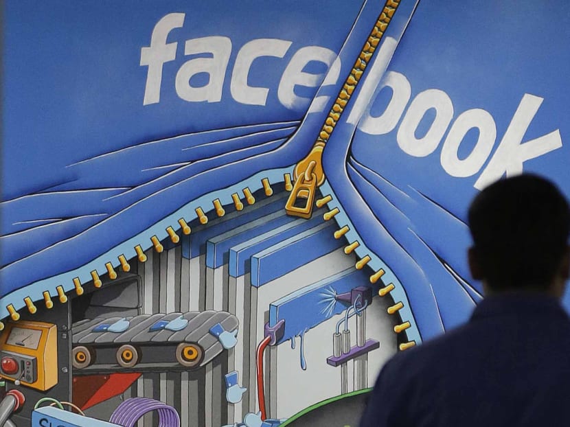 A Facebook employee walks past a sign at Facebook headquarters in Menlo Park, Calif., Friday, March 15, 2013. Photo: AP