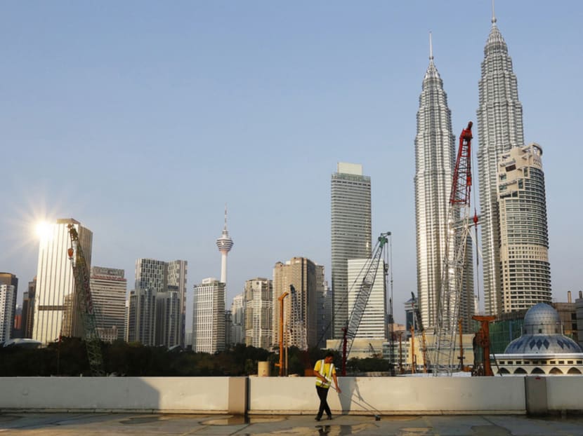A foreign worker sweeps a car park in front of the Petronas Towers in Kuala Lumpur, January 26, 2015. According to local media, there are an estimated 6.7 million foreign workers in Malaysia but only 2.1 million have valid work permits. REUTERS/Olivia Harris (MALAYSIA - Tags: BUSINESS SOCIETY IMMIGRATION)