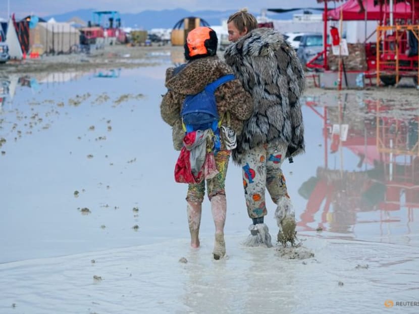 Dub Kitty and Ben Joos, of Idaho and Nevada, walk through the mud at Burning Man after a night of dancing with friends in Black Rock City, in the Nevada desert, after a rainstorm turned the site into mud on Sept 2, 2023.