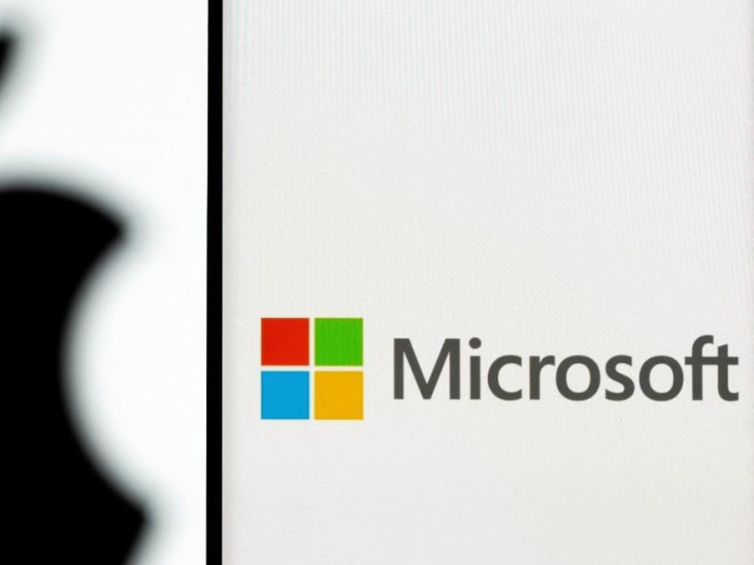 Microsoft logo is seen on the smartphone in front of displayed Apple logo in this illustration taken, July 26, 2021