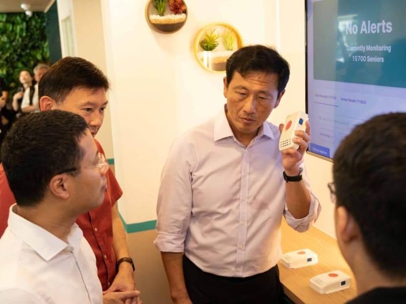 Health Minister Ong Ye Kung holding the "wireless alert alarm system" at the NTUC Health Active Ageing Centre on Nov 16, 2023, as National Development Minister Desmond Lee and Acting Transport Minister Chee Hong Tat look on.