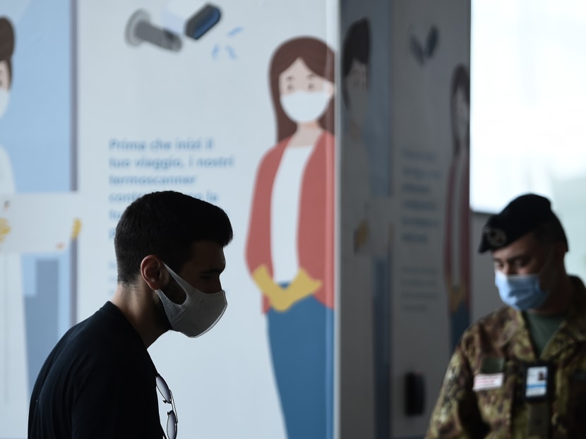 A traveller walks past a soldier at Rome's Fiumicino airport on June 3, 2020, as airports and borders reopen for tourists and residents free to travel across the country, within the Covid-19 infection, caused by the novel coronavirus.