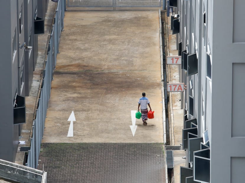 A man walks along a housing block within Toh Guan Dormitory on April 7, 2020.