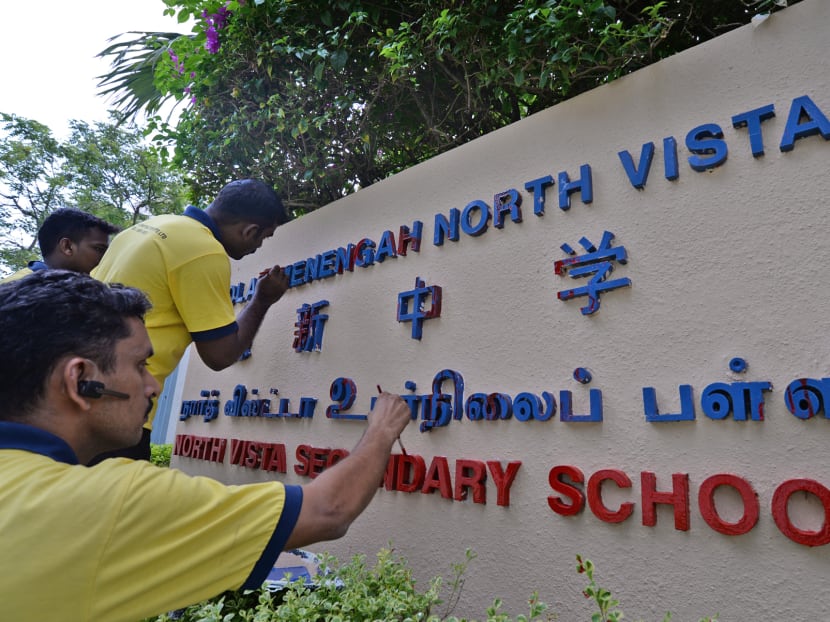 Contractors painting over the North Vista Secondary School sign after having been allegedly splashed with paint by loansharks. Photo: Robin Choo