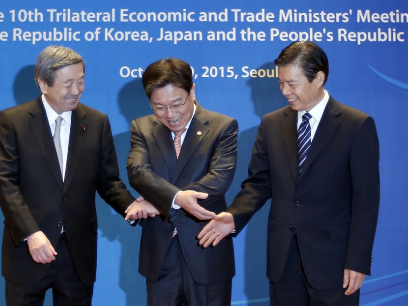 South Korea's Trade, Industry and Energy Minister Yoon Sang-jick, centre, tries to hold hands to posing for the media with Japan's Economy, Trade and Industry Minister Motoo Hayashi, left, and China International Trade Representative Zhong Shan, right, before the 10th trilateral economic and trade ministers' meeting in Seoul, South Korea, Oct 30, 2015. Photo: AP South Korea's Trade, Industry and Energy Minister Yoon Sang-jick, centre, tries to hold hands to posing for the media with Japan's Economy, Trade and Industry Minister Motoo Hayashi, left, and China International Trade Representative Zhong Shan, right, before the 10th trilateral economic and trade ministers' meeting in Seoul, South Korea, Oct 30, 2015. Photo: AP