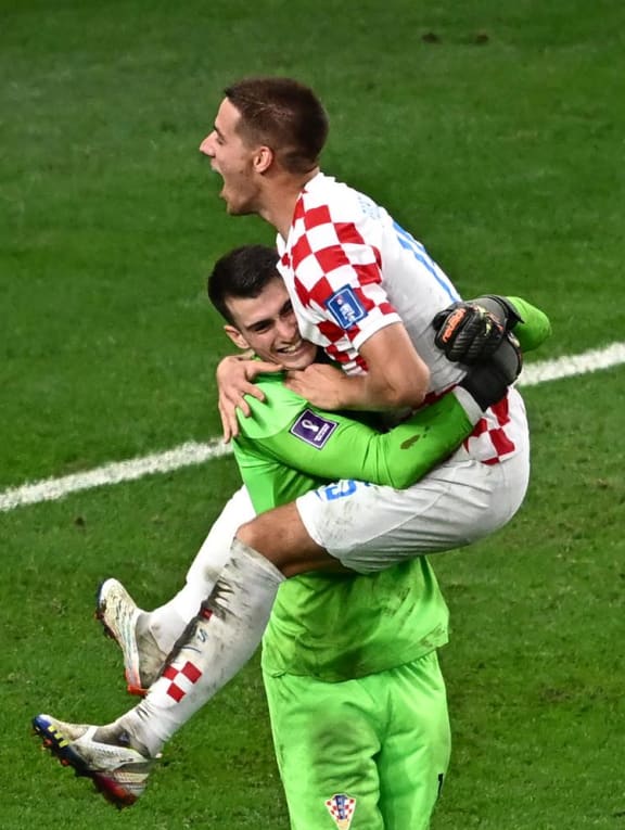 Croatia's midfielder Mario Pasalic celebrates with goalkeeper Dominik Livakovic after scoring the winning penalty kick during the Qatar 2022 World Cup round of 16 football match between Japan and Croatia at the Al-Janoub Stadium in Al-Wakrah, Doha on Dec 5, 2022.