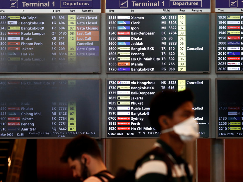 A man wearing a mask passes a flight information board at Changi Airport, following the Covid-19 outbreak in Singapore. On March 11, 2020, the Ministry of Health said that eight out of the 12 newly confirmed infections in the country were imported cases.