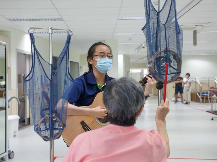 Ms Karen Koh playing the guitar as a patient at St Luke’s Hospital strikes a tambourine during a music therapy session. Ms Karen Koh playing the guitar as a patient at St Luke’s Hospital strikes a tambourine during a music therapy session.