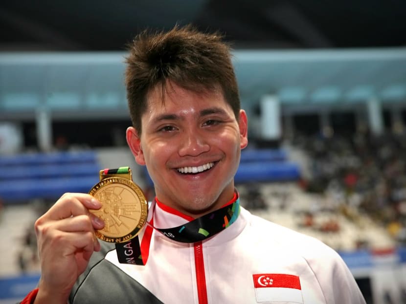 Joseph Schooling holds out his gold medal after coming in first during the men's 50m butterfly at the 2018 Asian Games in Jakarta on Aug 23, 2018.