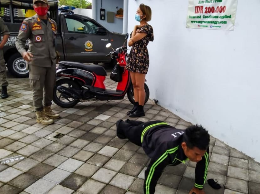 An undated handout picture released on Jan 20, 2021 by Bali's Satpol PP, the provincial public order agency, shows an official looking on while a man performs push-ups as punishment for not wearing or improperly wearing face masks amid the Covid-19 coronavirus pandemic. An undated handout picture released on Jan 20, 2021 by Bali's Satpol PP, the provincial public order agency, shows an official looking on while a man performs push-ups as punishment for not wearing or improperly wearing face masks amid the Covid-19 coronavirus pandemic.