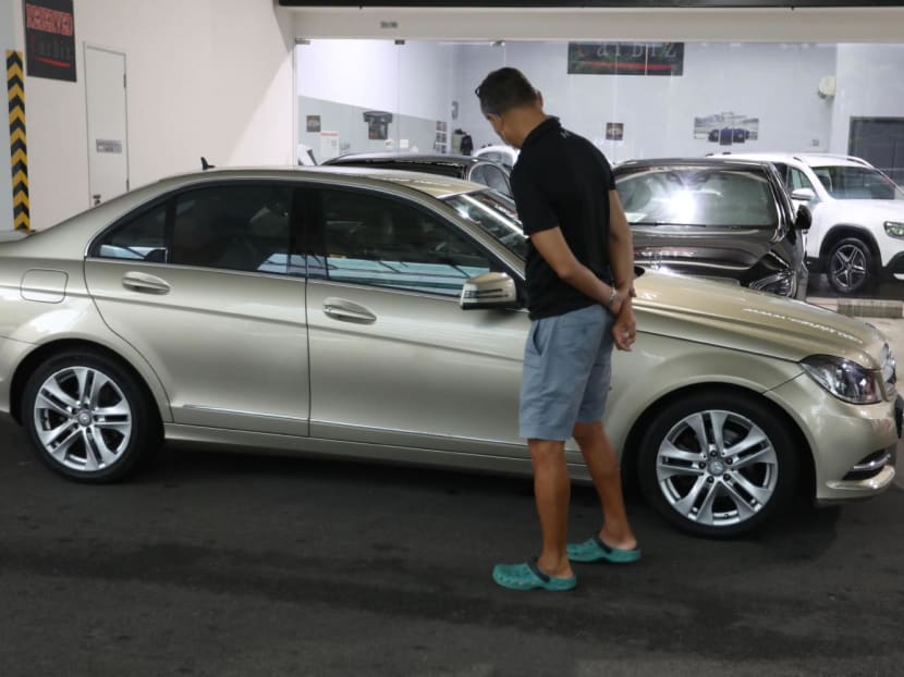 A man looking at a car that was being sold in a showroom in Singapore.