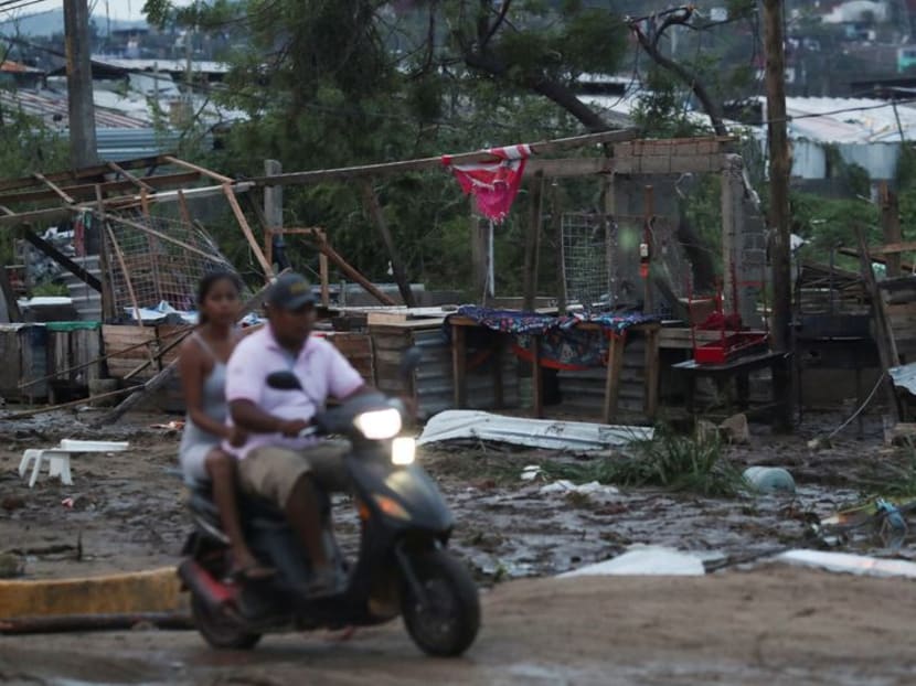 People on a vehicle pass by street stalls damaged by Hurricane Otis near Acapulco, in the Mexican state of Guerrero, Mexico on Oct 25, 2023.