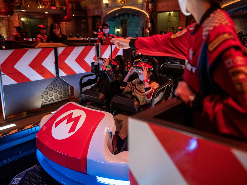 In this picture taken on March 17, 2021, fans of Universal Studios Japan wear themed augmented reality goggles for the "Mario Kart" ride during a media preview of the Super Nintendo World at Universal Studios Japan in Osaka.