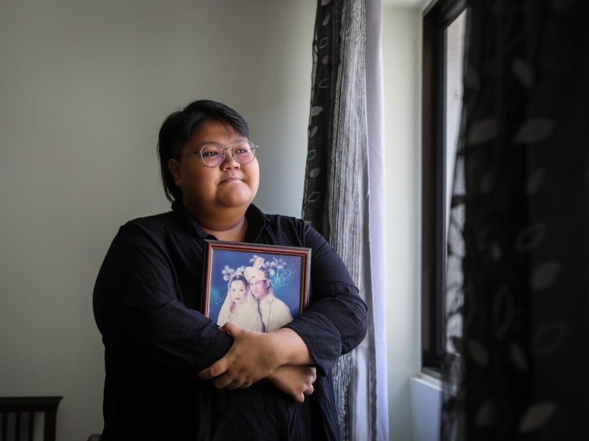Gen Z Speaks writer Qistina Hatta holds a wedding photograph of her father and late mother.