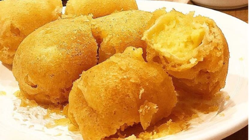 Tampilan close-up durian goreng keemasan dengan lapisan renyah, disajikan di atas piring putih