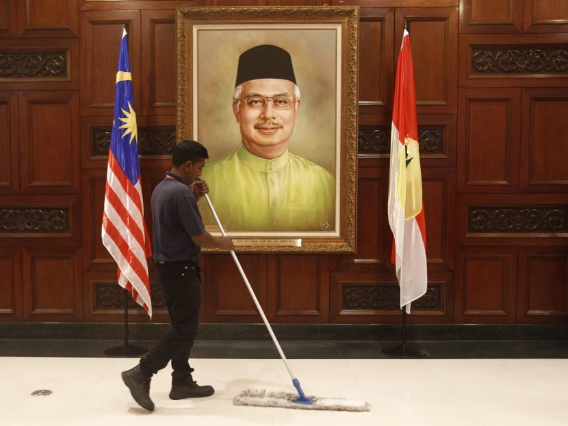 A maintenance worker works near a portrait of Malaysian Prime Minister Najib Razak during the 69th United Malays National Organisation's (UMNO) general assembly in Kuala Lumpur, Malaysia, Tuesday, Dec. 8, 2015. Photo: AP