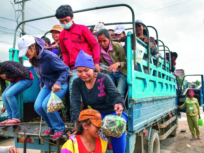 Workers alighting from a truck in a garment manufacturing district in Phnom Penh. Cambodia has ratified UN conventions designed to keep teens under age 18 from hazardous work, but the definitions of hazards are not always clear. Photo: Bloomberg