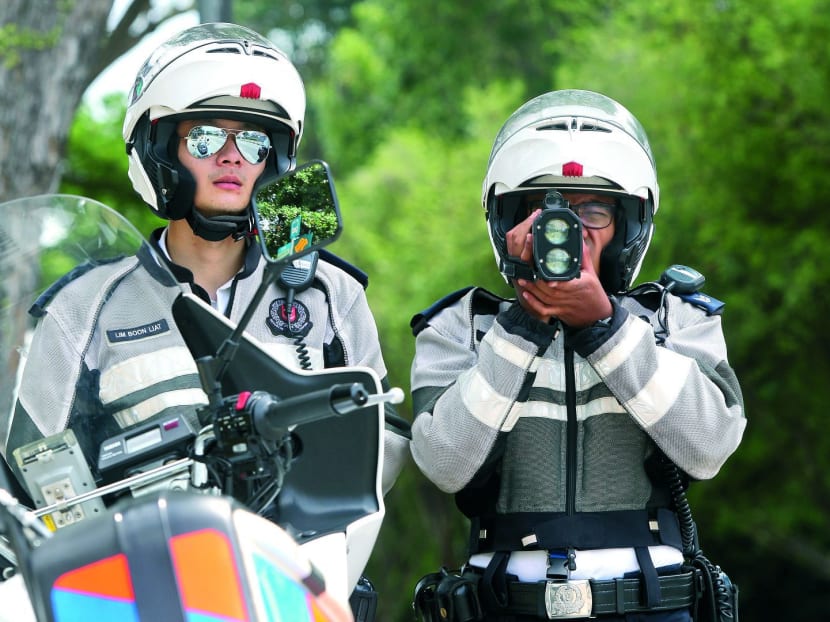 Traffic police officers keeping an eye out for speeding motorists near Temasek Secondary School, Upper East Coast Road with the aid of a laser gun. Photo: Don Wong