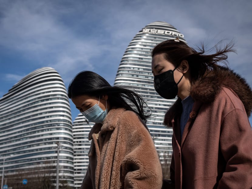 People wearing face masks as a preventive measure against the Covid-19 coronavirus walk on a street in Beijing on March 10, 2020.