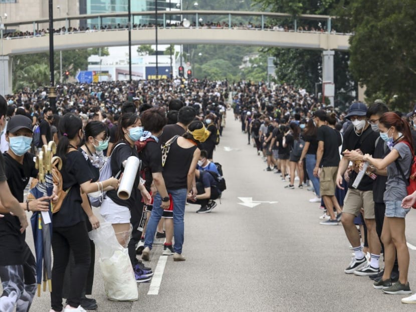 Extradition bill protesters pass helmets, umbrellas and other supplies down a human chain at a protest in Sha Tin on Sunday, July 14, 2019.