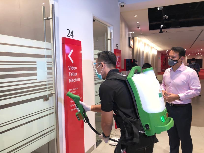 Mr Zaqy Mohamad, Senior Minister of State for Manpower, watching a cleaning demonstration at a DBS bank branch on Oct 29, 2020, before giving the media details on a new workgroup to help lower-wage workers.