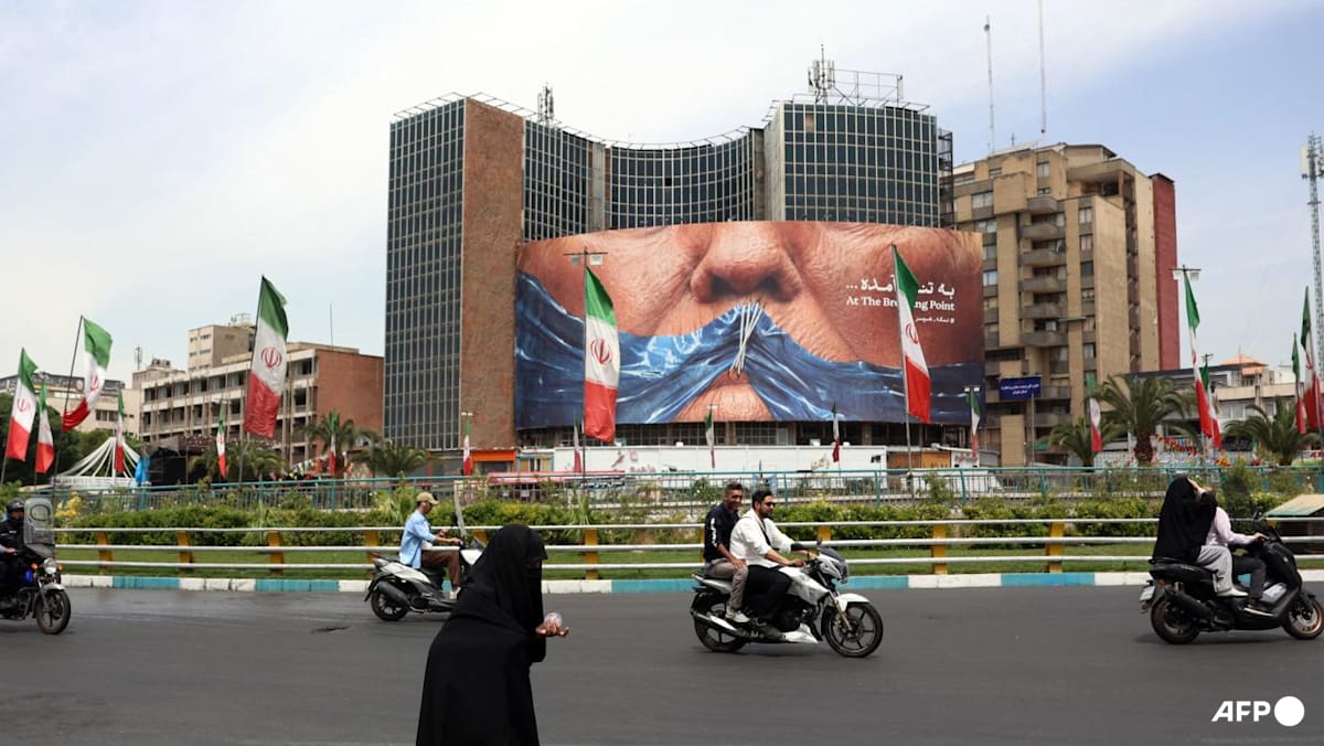 Iranians drive past a billboard featuring US President Donald Trump and the Strait of Hormuz, erected on Valiasr Square in Tehran, on May 28, 2026. (File photo: AFP)