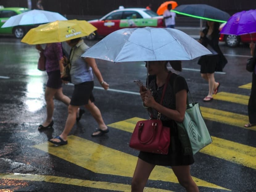 Pedestrians walk with umbrellas as they cross a road during heavy rain in Kuala Lumpur.  Low wages and the high cost of living have made it hard for borrowers of the government’s higher education loan scheme (PTPTN) to pay back their debts even as they are offered discounts to do so in Budget 2018. Photo: AFP