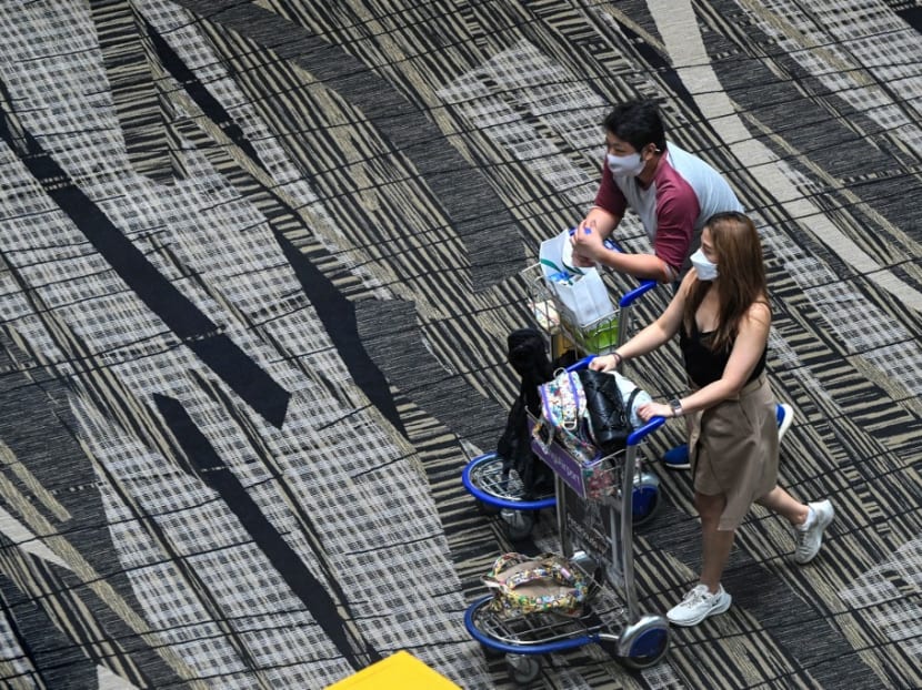 Travellers walk along the transit hall of Changi International Airport in Singapore on March 11, 2022.
