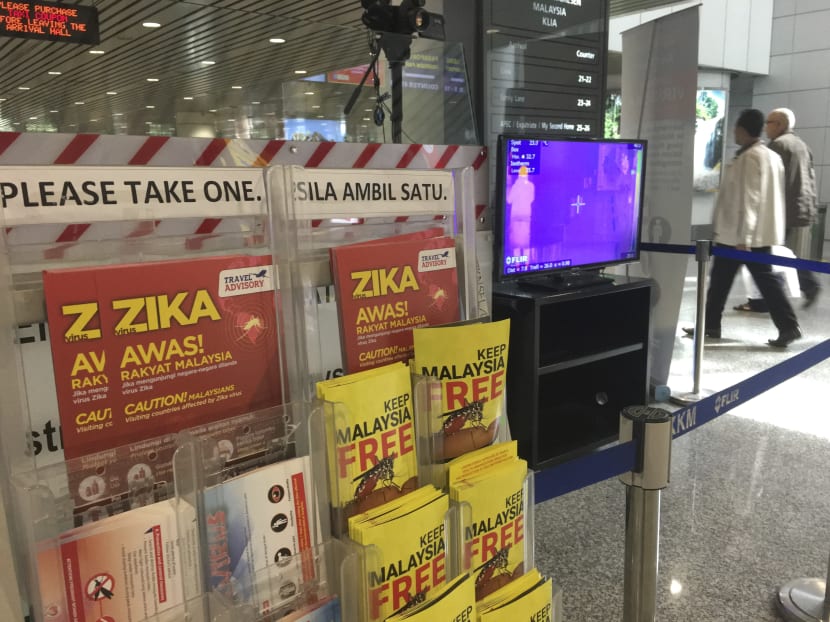 Travellers walk past travel advisory on the Zika virus infection and a body temperature scanner in Kuala Lumpur International Airport (KLIA) on Aug 28, 2016. Photo: AP Travellers walk past travel advisory on the Zika virus infection and a body temperature scanner in Kuala Lumpur International Airport (KLIA) on Aug 28, 2016. Photo: AP