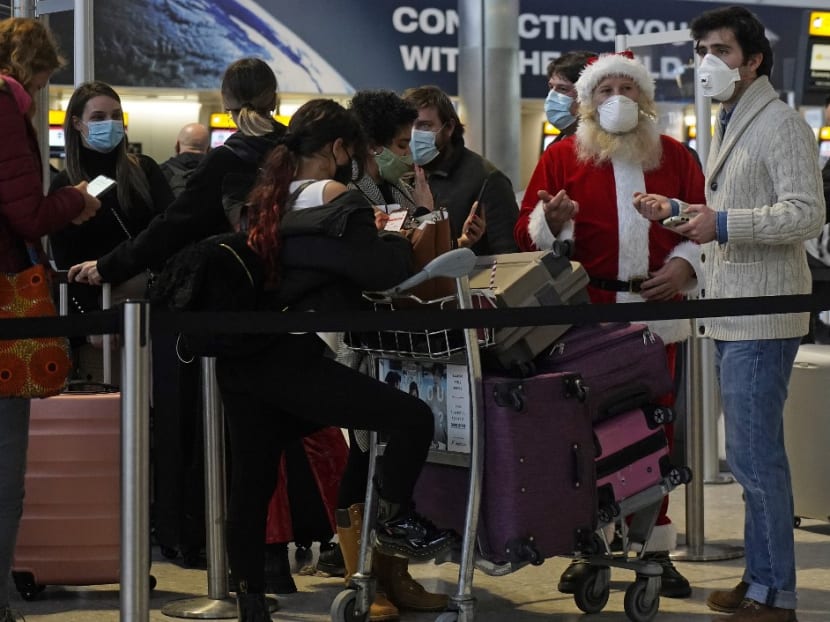 Travellers, one dressed in a Father Christmas outfit and all wearing face coverings, queue with their luggage in the departures hall at Terminal 2 of Heathrow Airport in west London on Dec 21, 2020, as a string of countries around the world banned travellers arriving from the UK, due to the rapid spread of a new, more-infectious coronavirus strain.