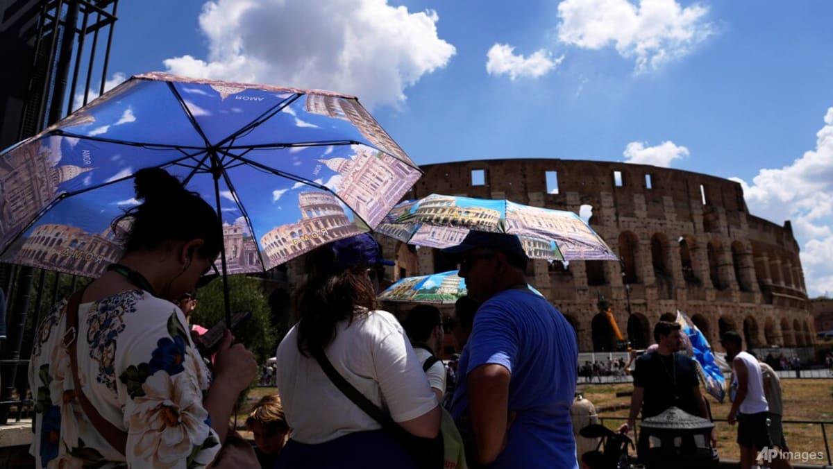 People stand under umbrellas in front of the Colosseum.