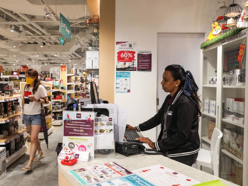 An employee at a ToTT store in i12 Katong sits on a chair behind the counter as she does administrative tasks on a computer. 