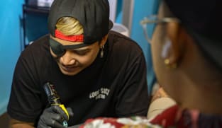 Tattoo artist Mohamed Tirana Mohamed Sufian working on a tattoo in his studio at Parklane Shopping Mall on Sept 16, 2024. 