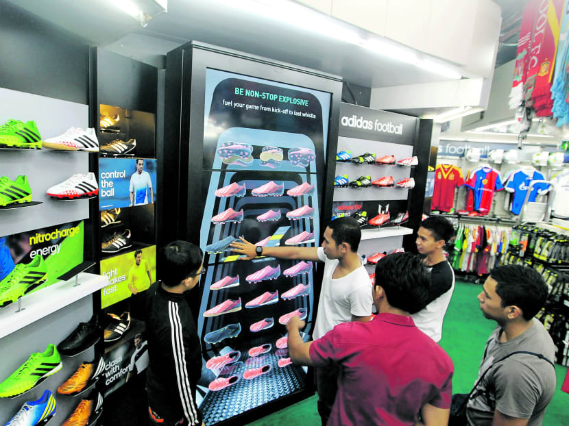Shoppers at Weston Corporation, Queensway Shopping Centre, trying out the new adidas Virtual Football Wall, with sales assistant Cris Zhang (left). Photo: Koh Mui Fong