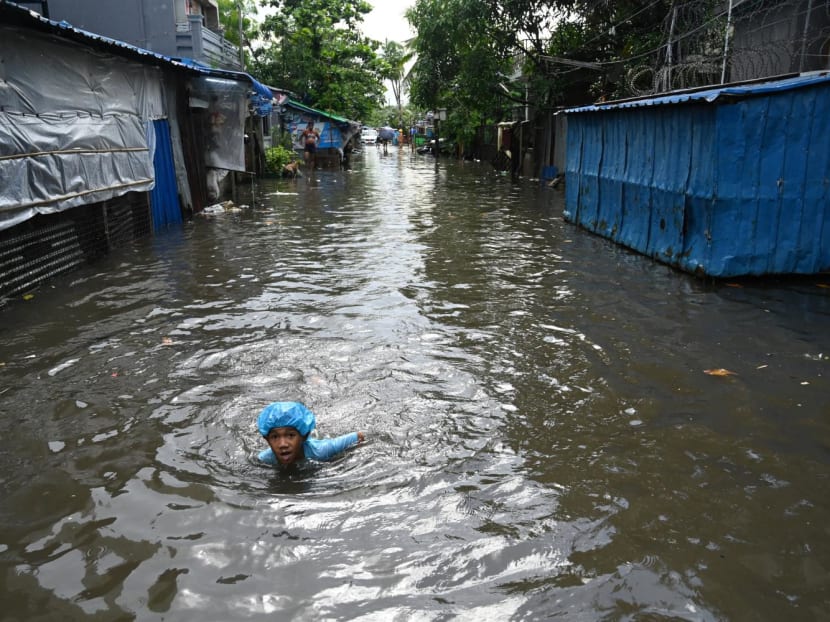 A boy swims through flood waters after heavy rain in Yangon on June 28, 2023.