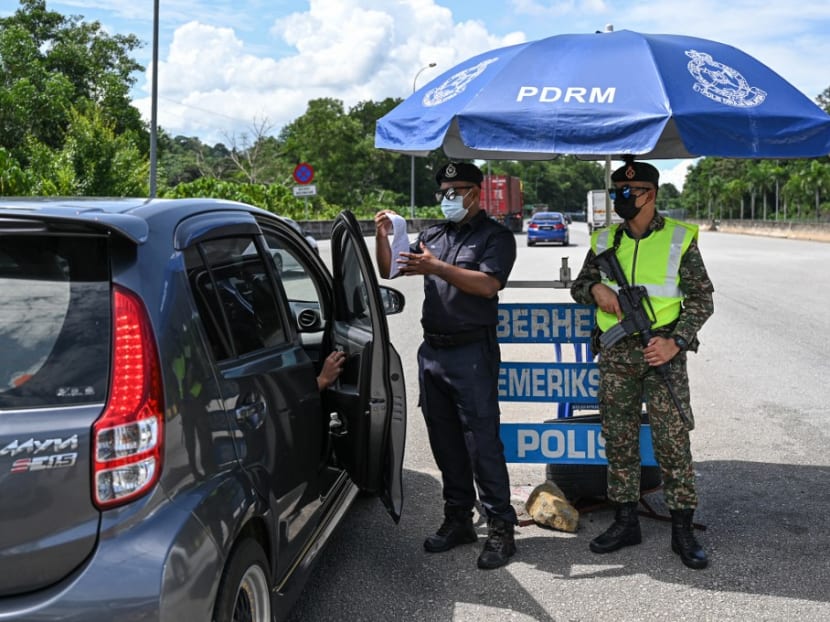 A policeman checks documents at a roadblock on the East Coast Expressway (Kuala Lumpur–Karak) during a partial lockdown set by authorities restricting travel within each state and district to curb the spread of the Covid-19, ahead of Aidilifitri, marking the end of the Islamic holy month of Ramadan, in Bentong on May 11, 2021.