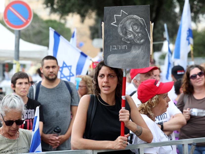 A woman holds a sign reading "destruction" in Hebrew with a drawing depicting Prime Minister Benjamin Netanyahu, as Israeli anti-government protesters attend a four-day sit-in near the parliament in Jerusalem on April 2, 2024.