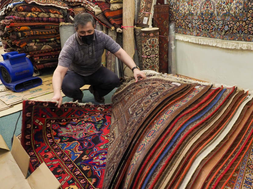 A shopkeeper at Bukit Timah Plaza uses a blower to dry carpets affected by flood waters that entered the shopping centre's basement area on Aug 24, 2021.