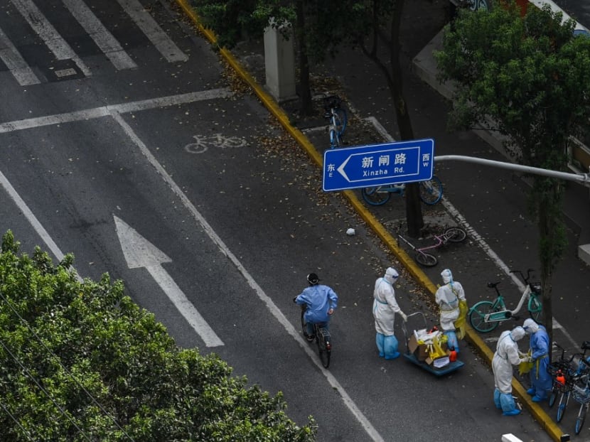Health workers wearing personal protective equipment (PPE) stand next to the entrance of a neighborhood during a Covid-19 lockdown in the Jing'an district in Shanghai on April 12, 2022. Health workers wearing personal protective equipment (PPE) stand next to the entrance of a neighborhood during a Covid-19 lockdown in the Jing'an district in Shanghai on April 12, 2022.
