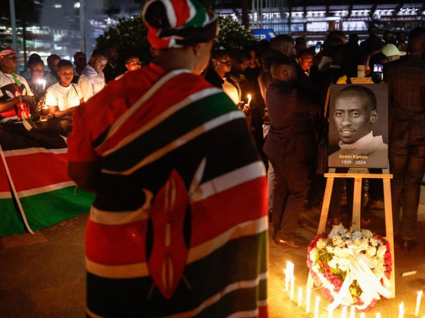 A woman wrapped with the national flag of Kenya pays her respect in front of a photo of late Kenyan marathon runner Kelvin Kiptum during a candle light vigil in Nairobi, on Feb 22, 2024. A woman wrapped with the national flag of Kenya pays her respect in front of a photo of late Kenyan marathon runner Kelvin Kiptum during a candle light vigil in Nairobi, on Feb 22, 2024.